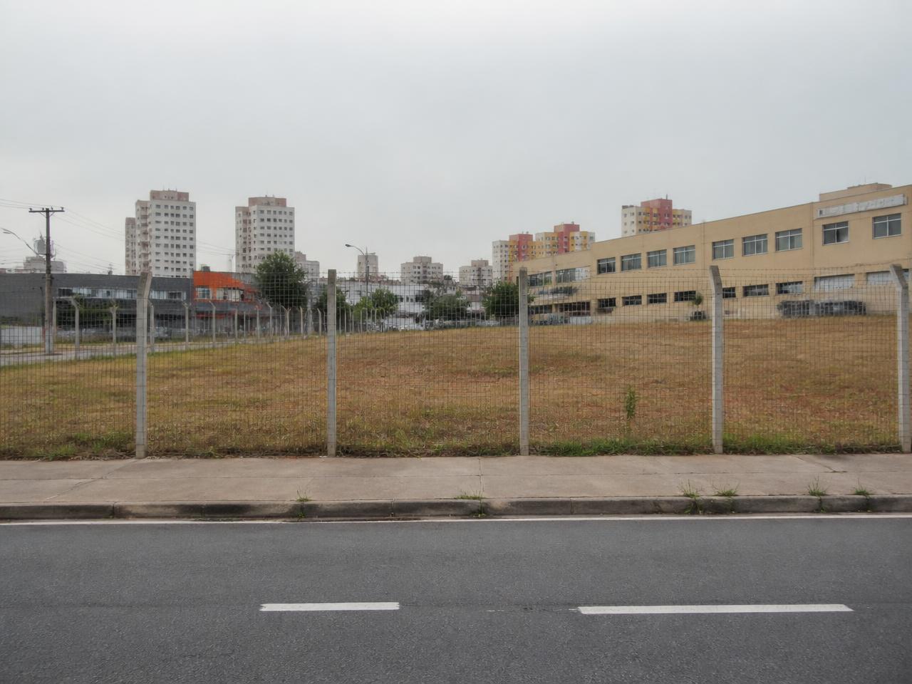 Acesso à área urbana em Barueri, com muro perimetral, construções existentes e áreas abertas